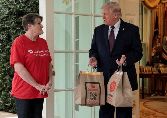 0c11e8701ff56f4b0414d4bee813c8b4_1776352830_8067.jpg 13일 미국 백악관에 배달온 배달 기사 샤론 시먼스(왼쪽)과 음식을 받는 도널드 트럼프 미국 대통령